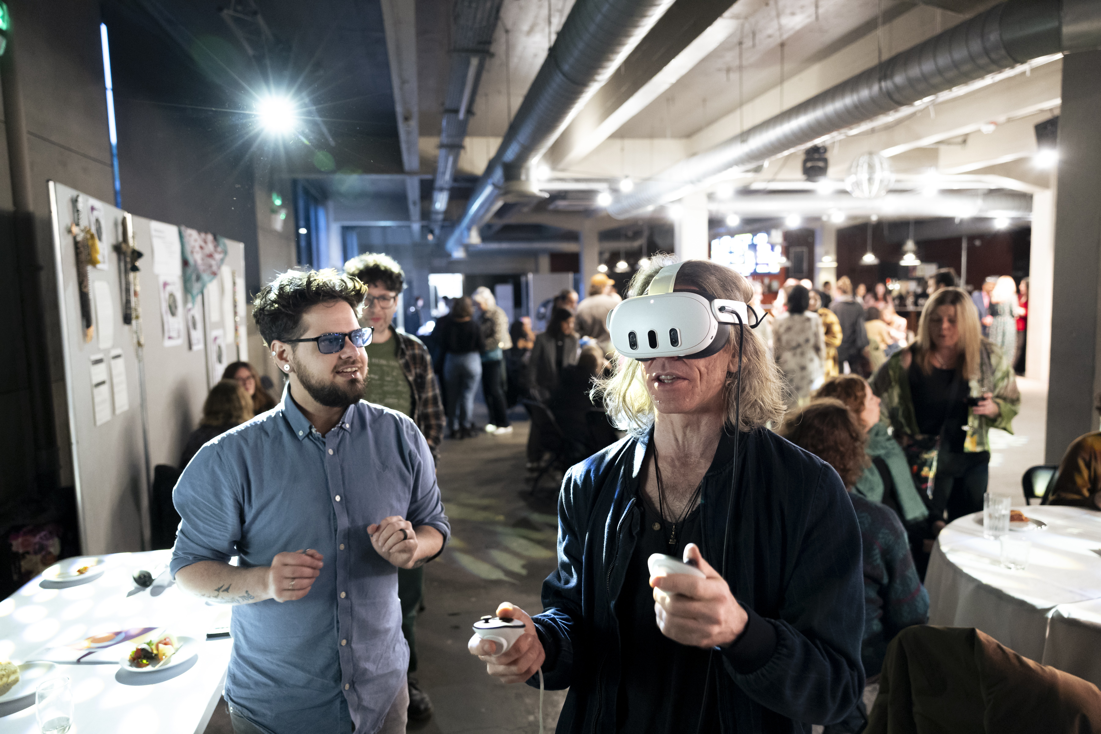 Someone wearing a VR headset with lots of people mingling in the background