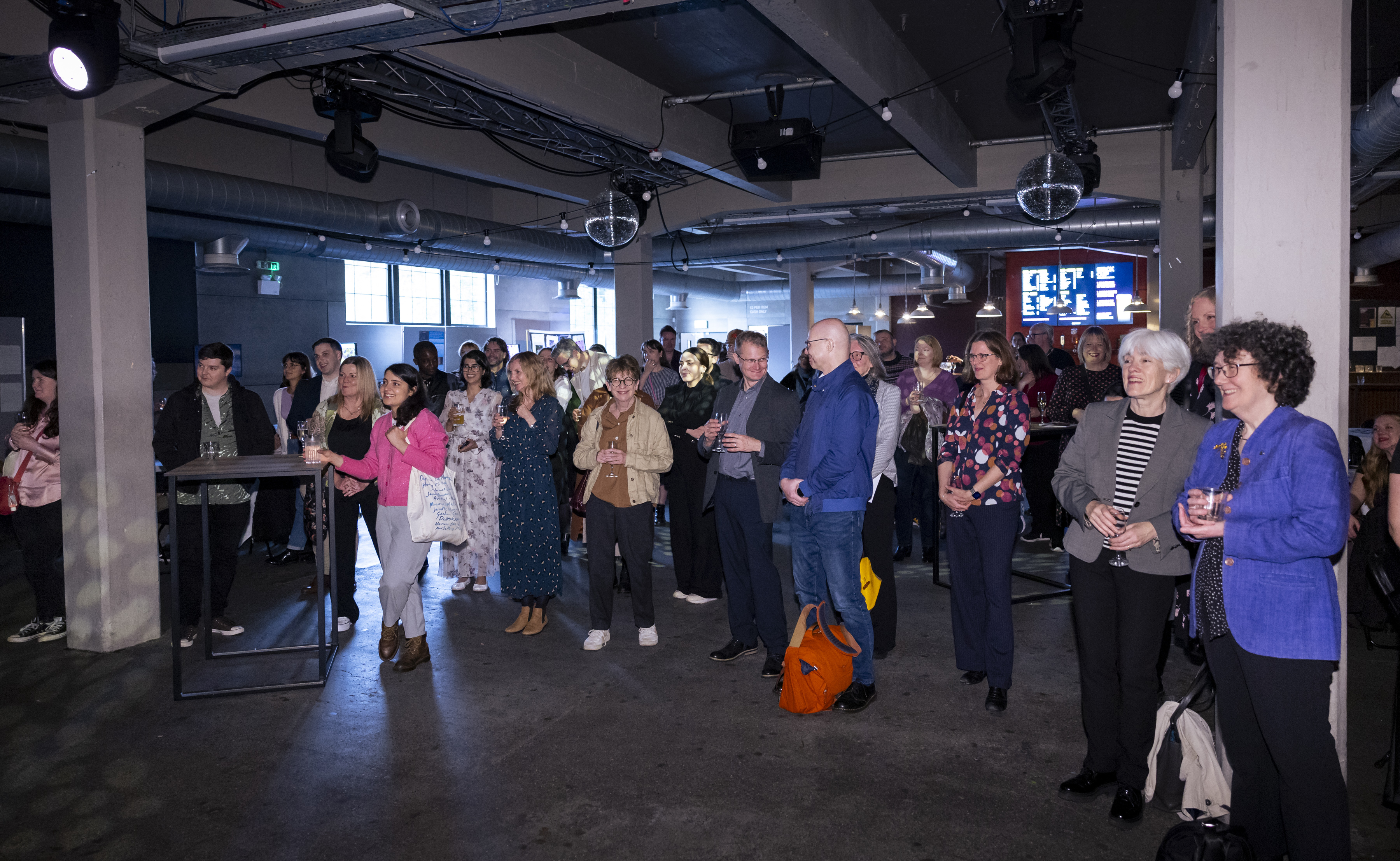 A large crowd of people at an indoor event all watching something offscreen