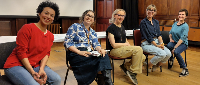 A group of four panelists seated in a row and smiling at the camera