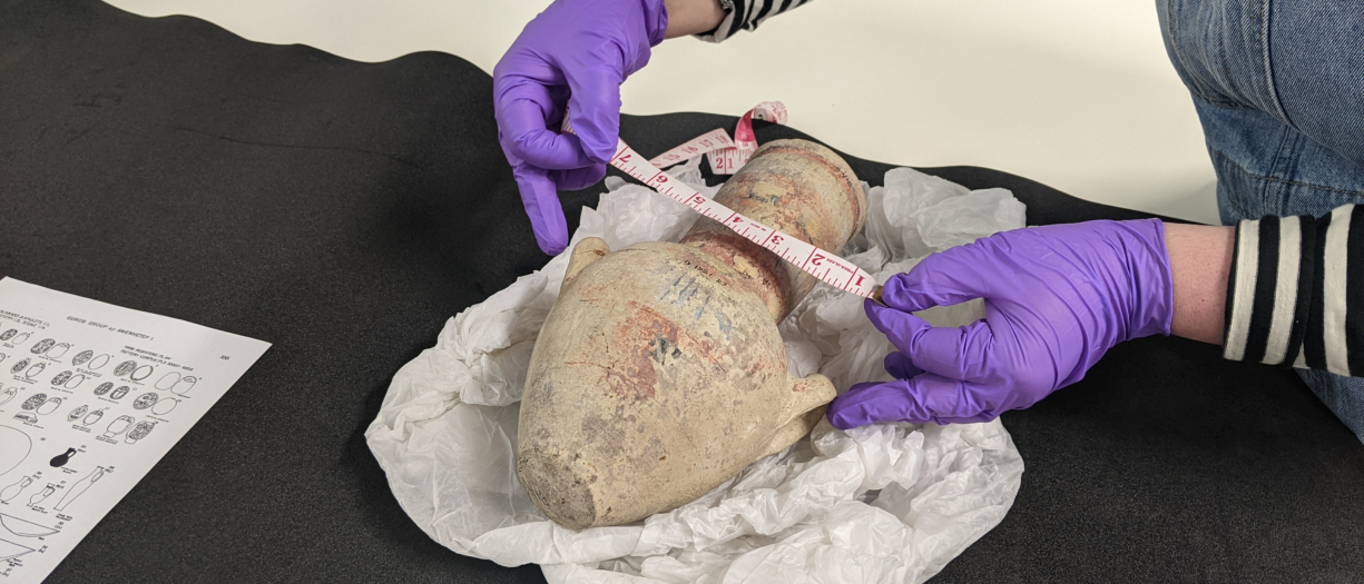 Close up of someone wearing gloves handling an ancient egyptian artefact