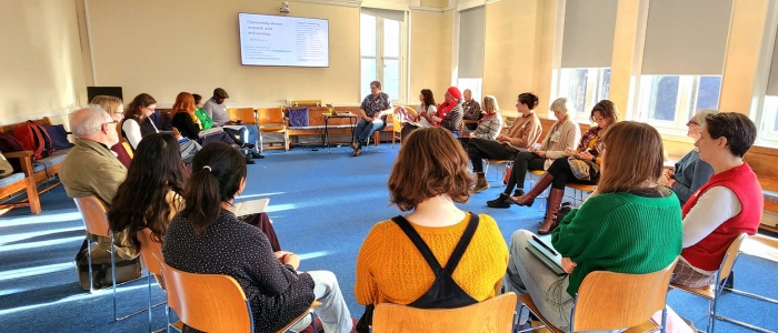 A group of people seated in a circle during a workshop discussion in a bright room