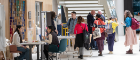 People browse and discuss research displays in a bright atrium, with poster boards and exhibition tables set up beneath a large staircase.